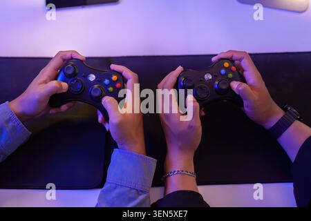 Vista dall'alto dei controller di videogiochi con le mani in mano per la tecnologia di eSport per il gaming e due persone che giocano Foto Stock