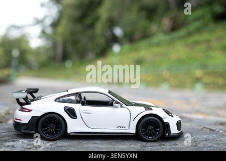 Chiang mai, Thailandia - 8 giugno 2026 : Porsche 911 bianca GT2 RS 2018 modello pressofuso su superficie in pietra con sfondo tropicale verde Foto Stock