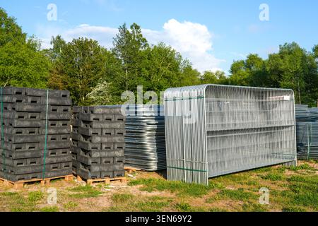 Pile di pannelli di recinzione temporanei in metallo e piedini di recinzione in plastica riciclata conservati all'esterno per la sicurezza dei cantieri e dei siti di eventi Foto Stock