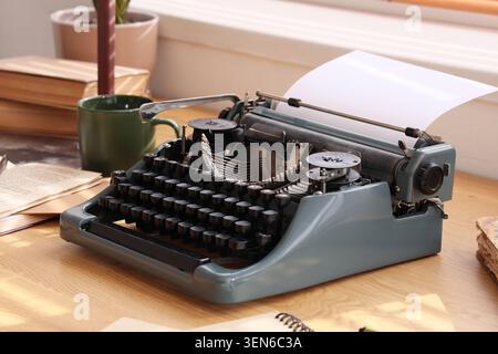 Macchina da scrivere vintage con carta bianca su scrivania in legno, scrittura creativa e concetto di narrazione, nostalgico strumento di comunicazione Foto Stock