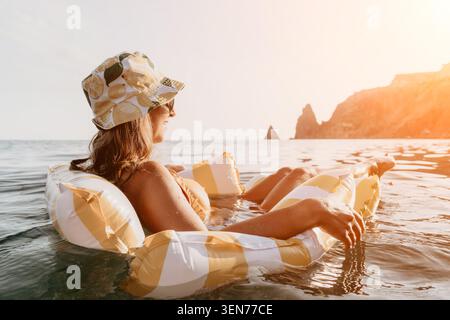 Donna, Spiaggia, relax: Una donna che indossa un cappello si rilassa su una zattera gonfiabile nell'oceano. Foto Stock