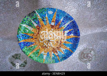 BARCELLONA, SPAGNA - 19 MARZO 2025: Una vista dettagliata delle piastrelle a mosaico del sole circolare sul soffitto della sala Ipostila a Park Guell, progettata da Foto Stock