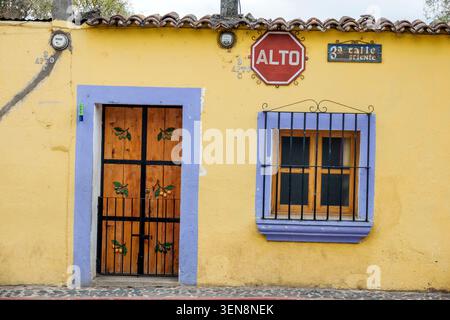 San Juan del Obispo Guatemala,Antigua Guatemala,3a Calle Oriente 3rd East Street,stop ALTO,facciata di case coloniali,architettura colorata,giallo stu Foto Stock