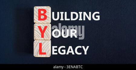 BYL sta costruendo il tuo simbolo legacy. Parole concettuali BYL costruisce la tua eredità su splendidi blocchi di legno. Splendido sfondo nero. Business BYL Building Foto Stock
