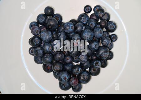Pile di mirtilli freschi a forma di cuore su piatto bianco Foto Stock