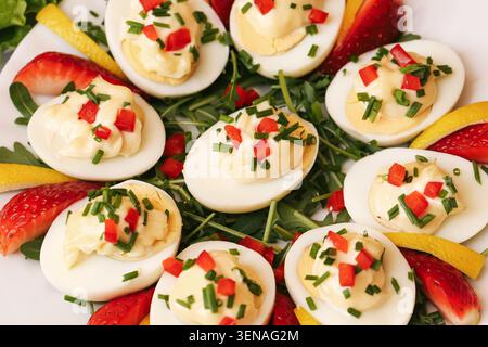 Uova ripiene decorate con verdure ed erbe fresche. Antipasti fatti in casa per buffet festivi, riunioni di famiglia e catering per feste. Foto Stock