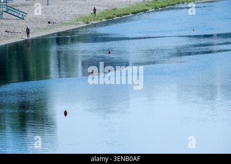 La luce del sole balla sulle dolci onde del fiume mentre le persone si godono una giornata serena in riva all'acqua. Hydropark, Kiev, Ucraina, 10 giugno 2026 Foto Stock