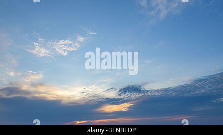 I raggi del sole si diffondono attraverso nuvole a strati durante un cielo colorato al tramonto. Foto Stock