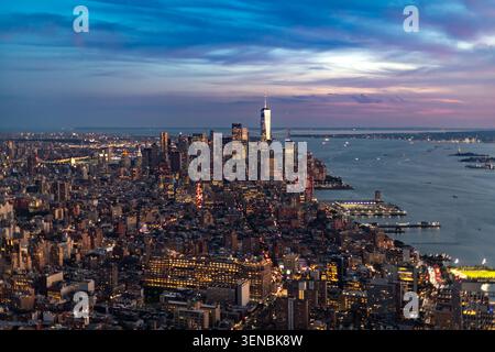 Questa spettacolare vista aerea di Manhattan cattura i grattacieli illuminati del centro cittadino e il fiume Hudson durante un tramonto colorato. Foto Stock