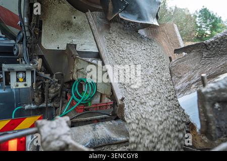 Il miscelatore versa calcestruzzo in un cantiere stradale in Inghilterra per pavimentazione e riparazioni Foto Stock