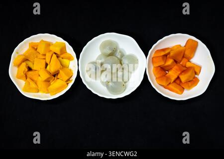 ciotole di frutta tropicale assortite con litchi di mango e papaya su sfondo nero per una nutrizione sana Foto Stock