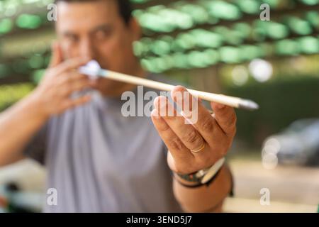 Uomo che tiene una freccia, che si prepara a tagliarla per la pratica del tiro con l'arco Foto Stock