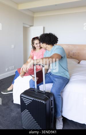 Diverse coppie sedute sul bordo del letto in camera, uomo con maniglia per valigia nera Foto Stock