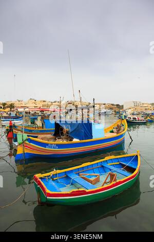 Tradizionali e colorati pescherecci maltesi (luzzu) ormeggiati nel porto di Marsaxlokk, Malta. Barche in legno dai colori vivaci che galleggiano nella famosa Foto Stock