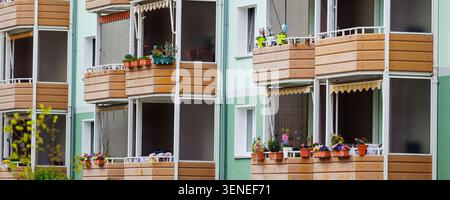 Edificio di appartamenti ristrutturato in stile tedesco con balconi decorati in legno e fiori in vaso. Il rosa ciliegia fiorisce l'albero primaverile Foto Stock