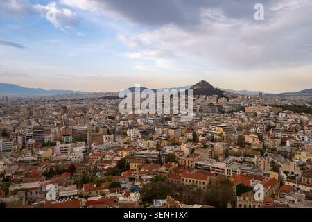 Vista panoramica di Atene, Grecia, con il Monte Licabetto che sorge sopra l'esteso paesaggio urbano sotto un cielo spettacolare. Foto Stock