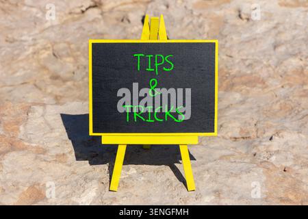 Simbolo delle parole "suggerimenti e trucchi". Parole concettuali suggerimenti e trucchi su una bellissima lavagna nera. Bellissimo sfondo in pietra. Suggerimenti e trucchi per il business motiva Foto Stock