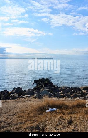Un affioramento roccioso contro la riva con la bassa marea. Sandy Hook, contea di Monmouth, New Jersey, Stati Uniti. Foto Stock