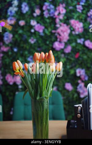 Un bouquet di tulipani arancioni in un vaso di vetro trasparente. Foto verticale Foto Stock