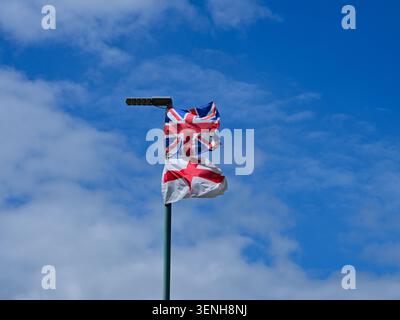 Union Jack e la bandiera inglese che sventolano insieme contro il cielo blu Foto Stock