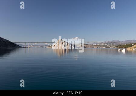 Ponte di Krka, struttura ad arco sul mare blu calmo con cielo limpido Foto Stock