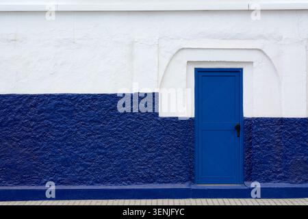 Una porta di legno blu luminoso su una tradizionale facciata di edificio bianco e blu ad Agaete in Spagna. Foto Stock