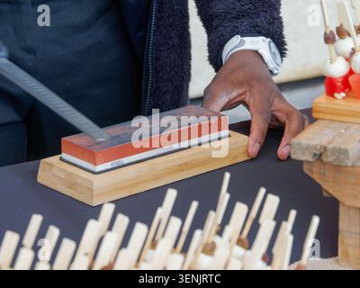 Primo piano di un prosciutto stagionato professionale tagliato a fette da una gamba di prosciutto con un coltello, tipico della salumeria europea, in Francia. Foto Stock