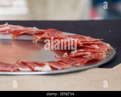 Primo piano di prosciutto stagionato a fette organizzato su un tabellone, tipico della salumeria europea, in Francia. Foto Stock