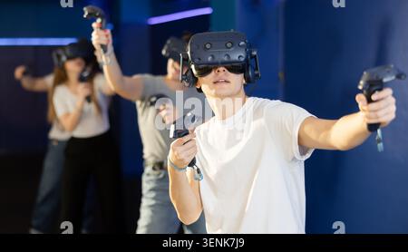 Ritratto di un giovane uomo con occhiali per realtà virtuale in piedi nella stanza Foto Stock