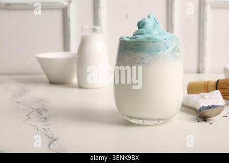 Bicchiere di dalgona blu con latte matcha e cucchiaio sul tavolo Foto Stock
