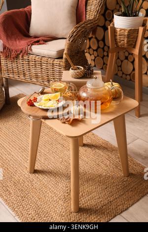 Teiera, tazza di tè verde con rowan, arredamento al limone e autunno sul tavolino da caffè in camera Foto Stock