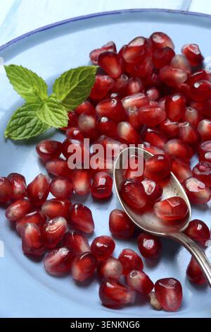 Semi di melograno e cucchiai sul piatto, Punica granatum Foto Stock