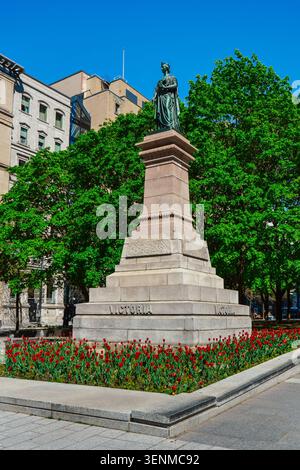 Montreal, Quebec, Canada - 21 maggio 2026: Queen Victoria Memorial accanto alle storiche facciate in pietra di Victoria Square. Foto Stock