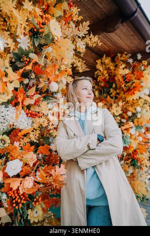 Donna in un Trench con fiori autunnali Foto Stock
