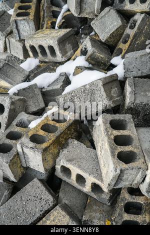 Una vista ravvicinata ad angolo alto cattura una grande pila di blocchi di cemento scartati, alcuni dei quali presentano uno scolorimento giallo-arancione e dei fori. Patch di Foto Stock