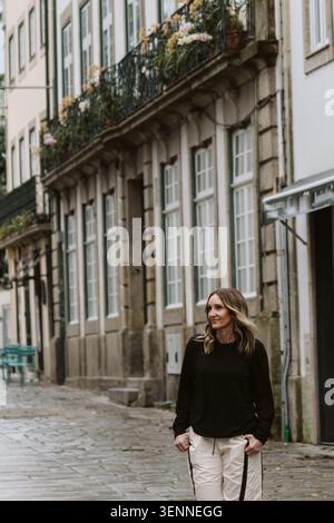 Donna elegante che cammina su una vecchia strada acciottolata Foto Stock