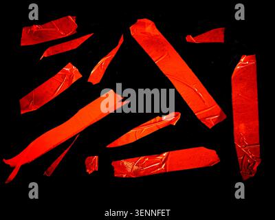 Pezzi strappati di nastro adesivo arancione visualizzati su sfondo nero, con forme e dimensioni diverse adatte per progetti di design e artigianato Foto Stock
