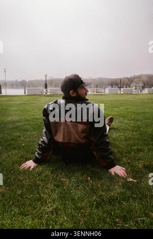 L'uomo con una giacca di pelle si rilassa sull'erba Foto Stock