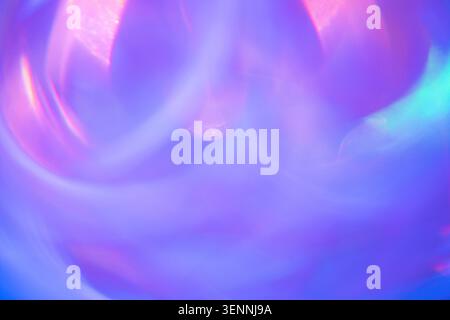 Immagine astratta con vivaci sequenze di luce in tonalità viola, blu e rosa, che creano un effetto vorticoso su uno sfondo morbido e sfocato Foto Stock