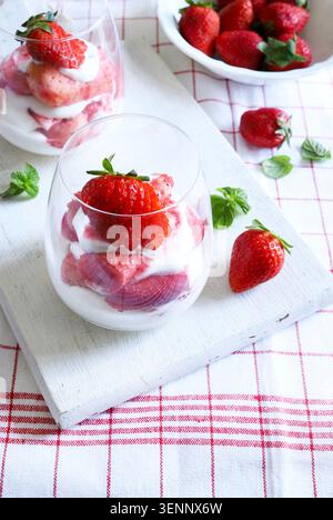 Tiramisù alle fragole. Autentico dessert estivo italiano con strati di panna, fragole fresche e biscotti serviti in bicchieri su sfondo bianco. Foto Stock