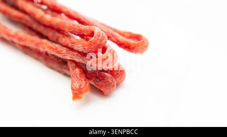 Salsiccia di maiale o di manzo, salsicce secche, bastoncini di carne affumicati. Lucidare il primo piano di salsicce asciutte, sottili e lunghe su sfondo bianco Foto Stock