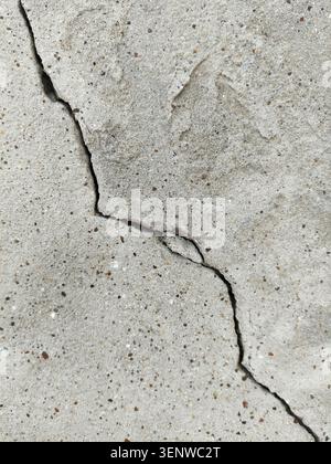 Una spaccatura diagonale irregolare su una superficie di cemento ruvido. Un vecchio muro di cemento rovinato, incrinato di un edificio. Distruzione dopo il terremoto. Copia spazio. R Foto Stock