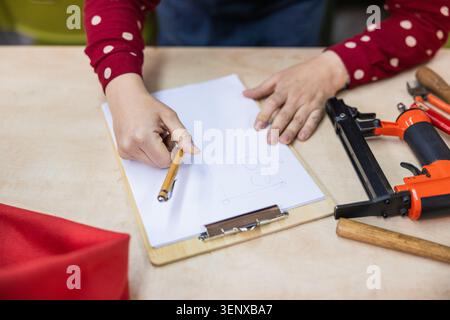 Persona che disegna il design della tappezzeria con gli attrezzi sul tavolo Foto Stock