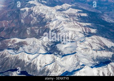Vista aerea delle creste innevate e delle profonde valli piene di ombre nelle Montagne Rocciose in Colorado, Stati Uniti, fotografate dall'altitudine di crociera Foto Stock