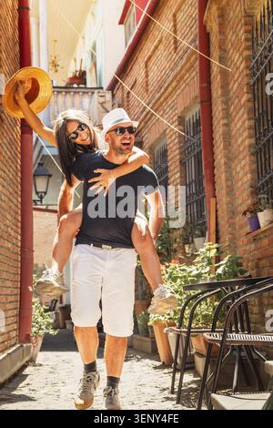 Allegri amici di coppia di mezza età che si divertono insieme godendosi una vacanza sulla strada della città vecchia. Sposi sposi spensierati innamorati che si divertono a divertirsi Foto Stock