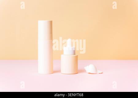 Confezione minimalista per la cura della pelle con bottiglie cosmetiche e conchiglia su sfondo pastello, concetto di benessere con spazio per copie e mockup. Foto Stock