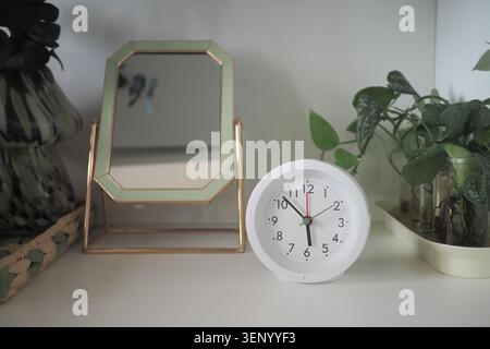 Orologio e specchio su uno scaffale in una stanza Foto Stock
