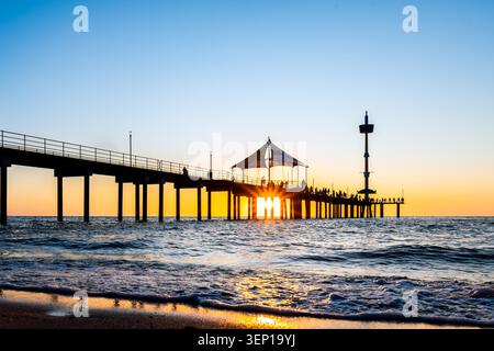Brighton Jetty silhouette con un caldo tramonto estivo con gente che si gode la serata estiva di guerra ad Adelaide, Australia meridionale Foto Stock