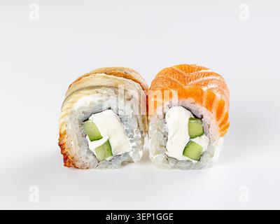 Primo piano di due sushi roll Philadelphia isolati su sfondo bianco. Un rotolo ricoperto di anguilla affumicata, l'altro con salmone fresco. Entrambi pieni di panna Foto Stock