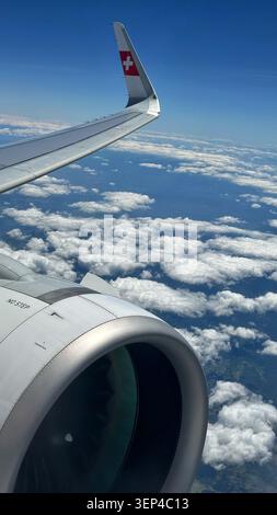 L'ala e il motore degli aeromobili della Swiss International Air Lines sono visibili dal finestrino del passeggero durante il volo in crociera sopra le nuvole sparse. Foto Stock